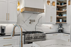 White kitchen with quartz backsplash, custom cabinetry and brass hardware