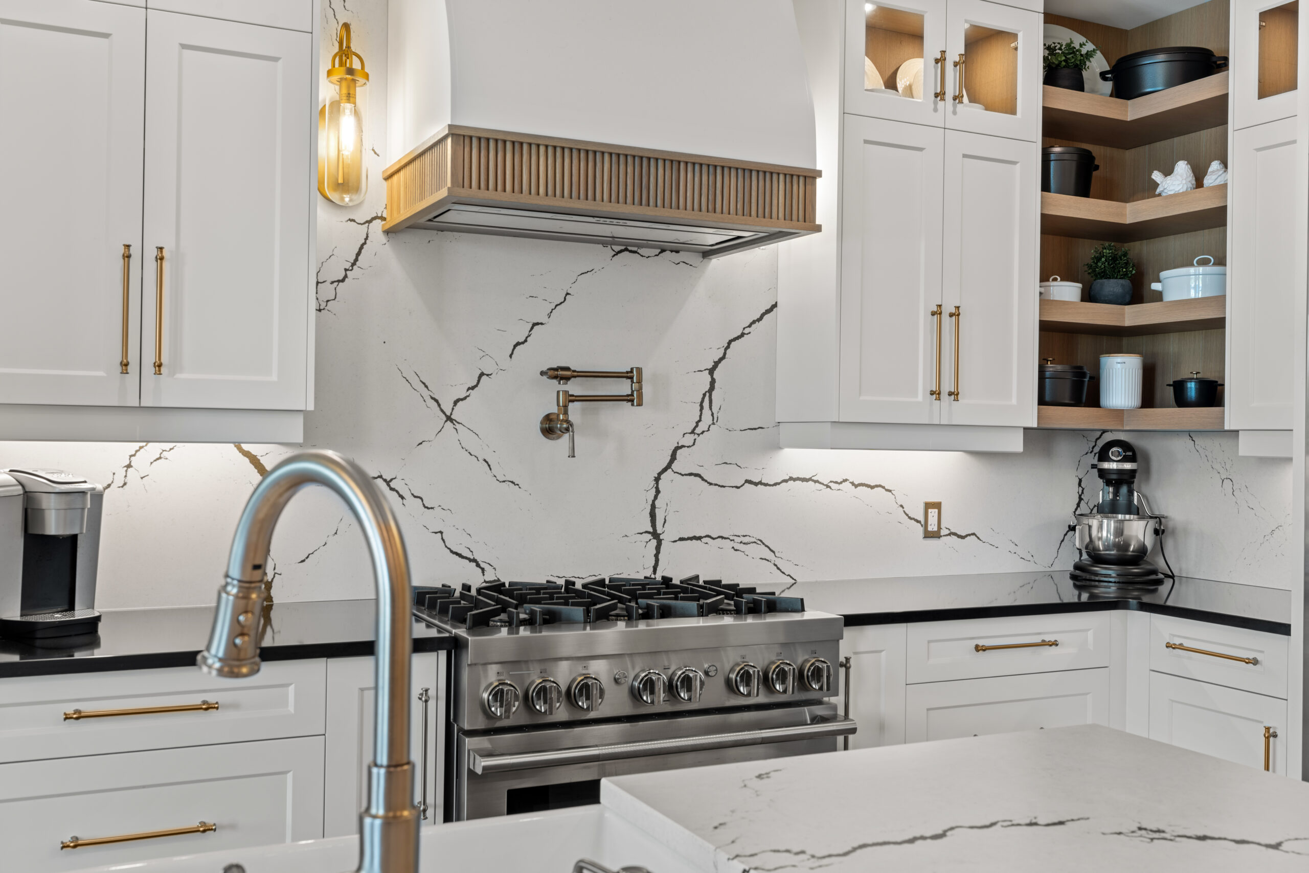 White kitchen with quartz backsplash, custom cabinetry and brass hardware